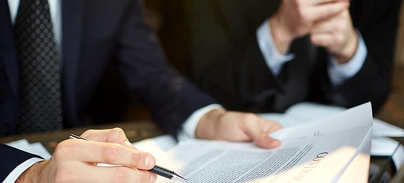 Ankara iş davası avukatı masanın üzerinde kağıt ve kalemlerin olduğu yerde konuşma yapıyor.
